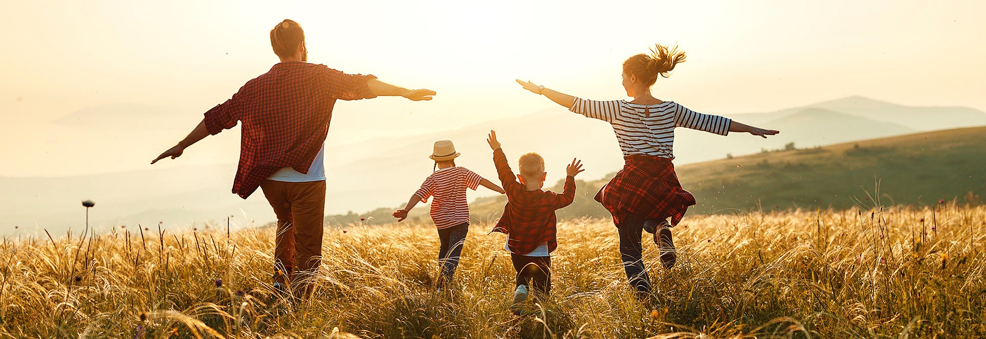 Famille courant dehors dans un champ par une journée ensoleillée.