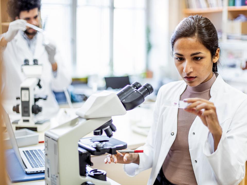 a-woman-in-a-lab-coat-looking-at-a-microscope
